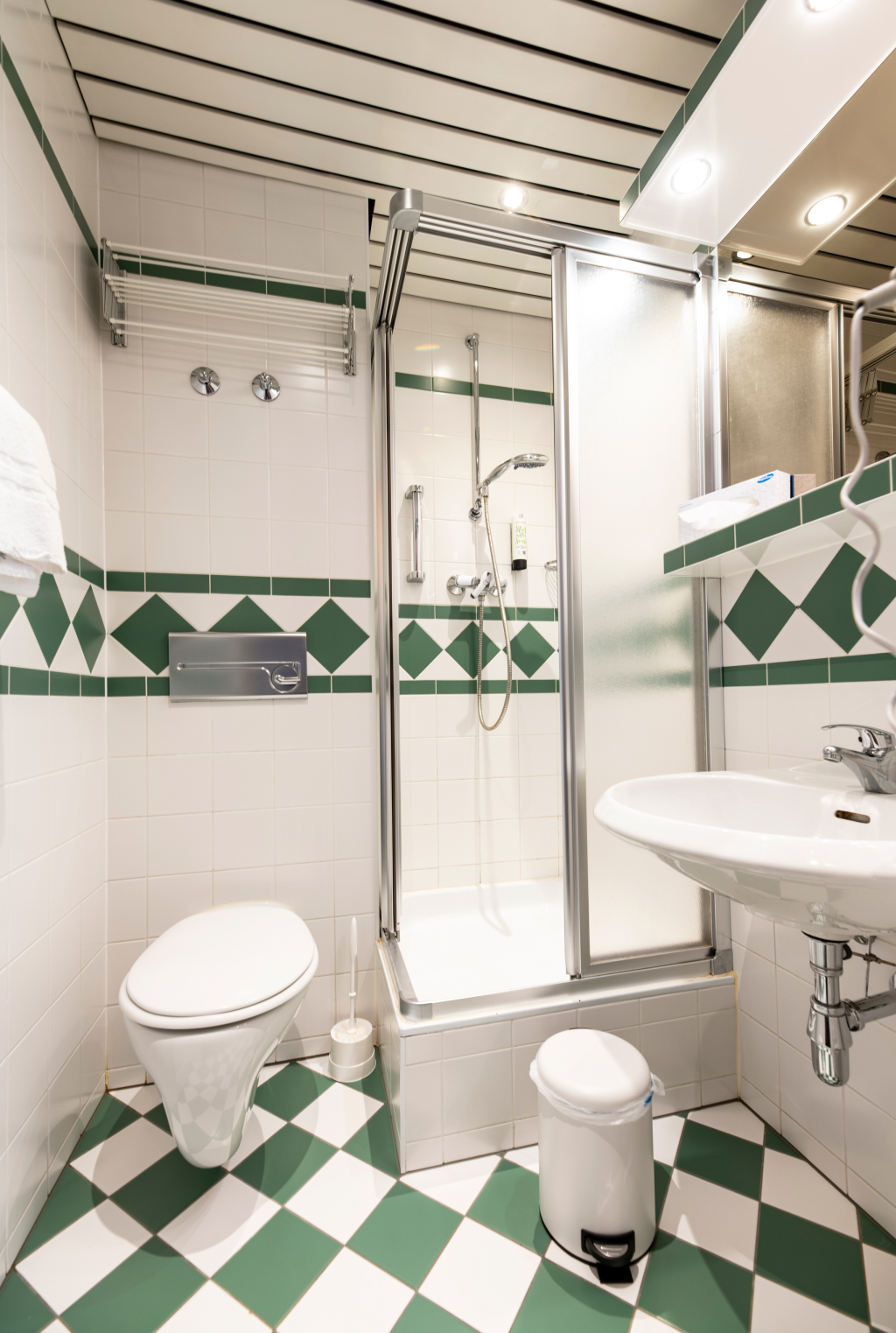 a bathroom with green and white tiles